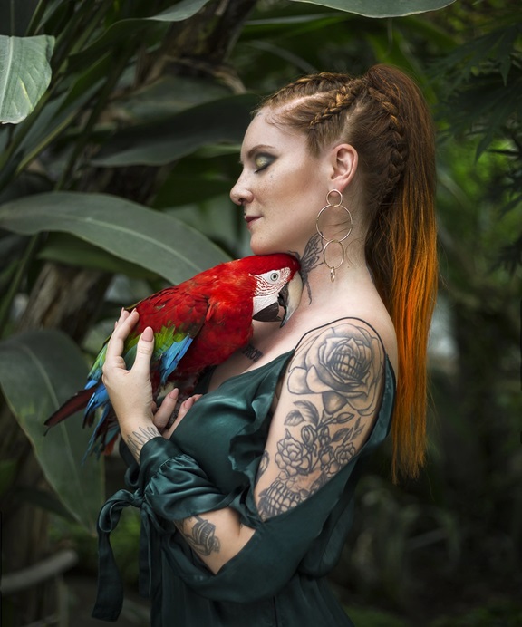 long haired Woman cuddling ara parrot in amazonia rainforest