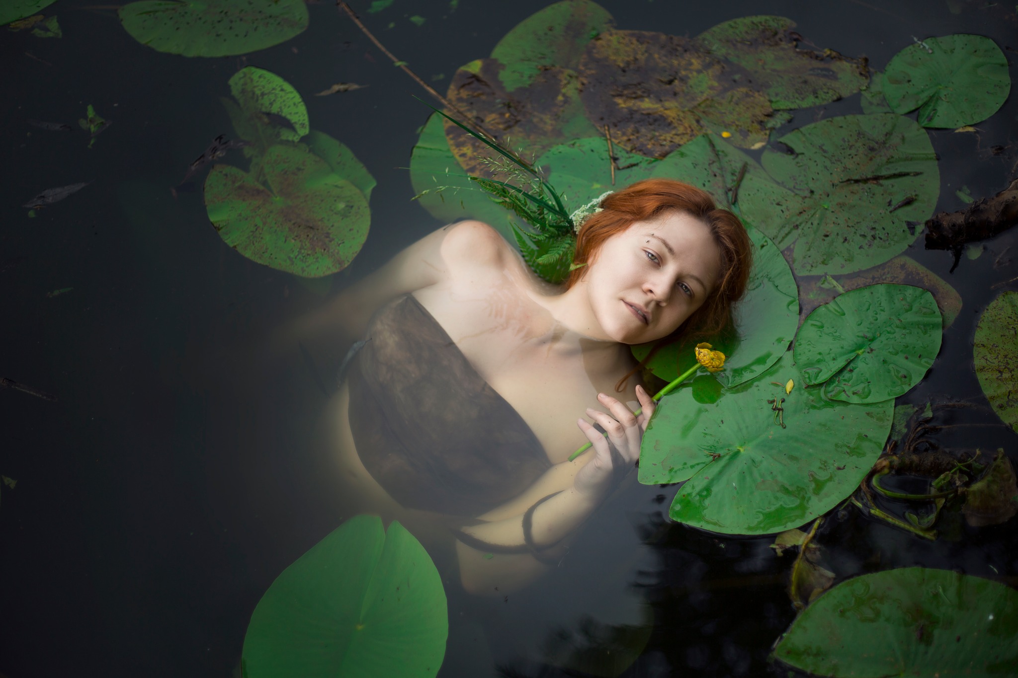 water nymph with ginger hair chilling in water with flower in her hand